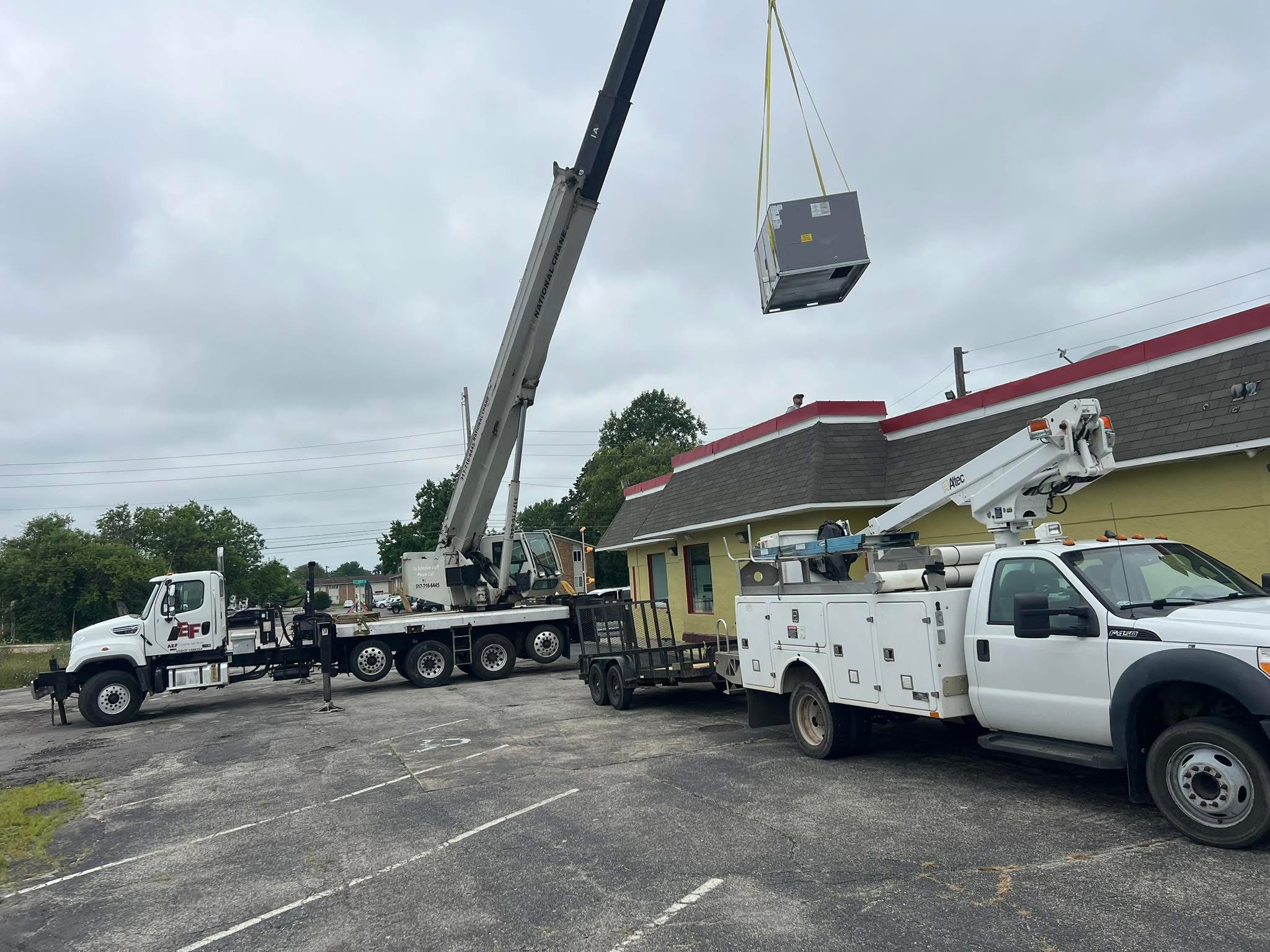 ACR crew installing commercial rooftop equipment with a crane
